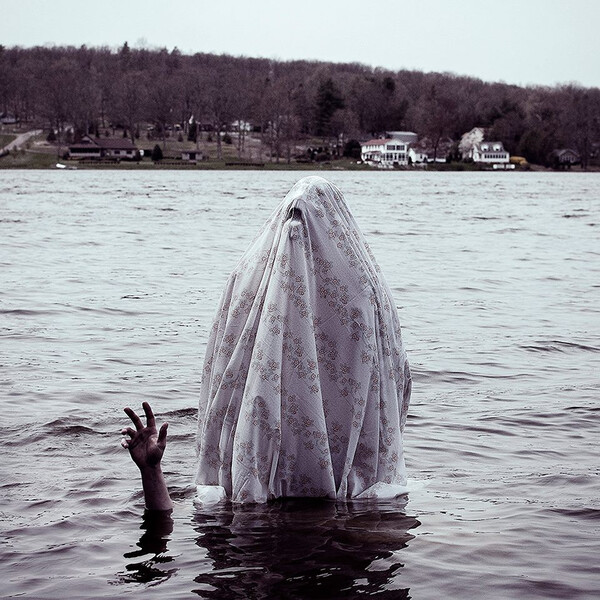 The cover of IDYLLS' Prayer for Terrene, a hooded figure rising out of a lake.