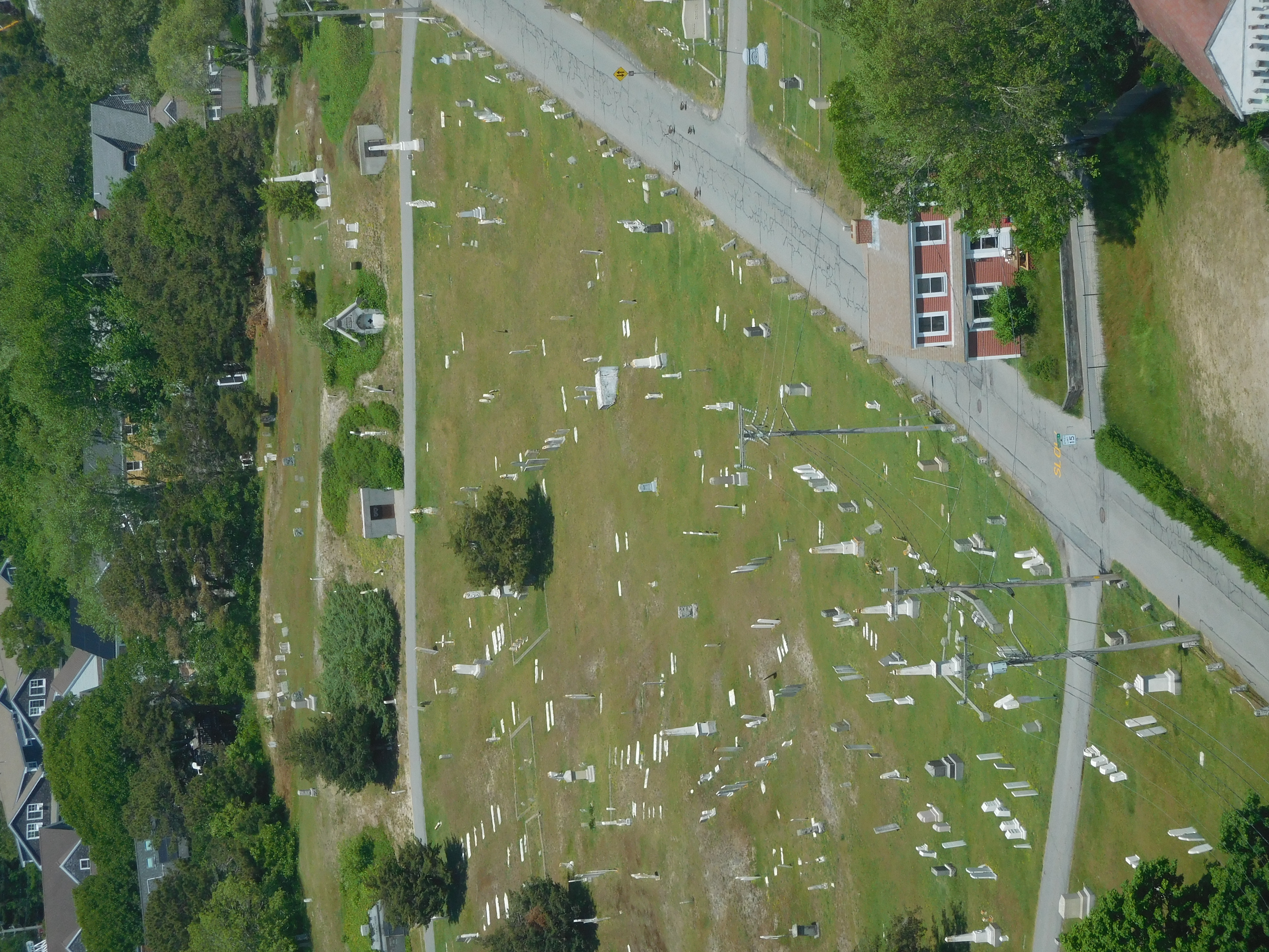a graveyard seen from above. there is a red house toward the bottom right corner.