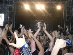 This may contain: a group of people at a concert with their hands in the air