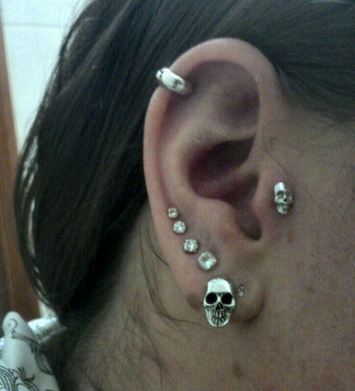 This may contain: a person with some piercings on their ears and behind them there is a skull