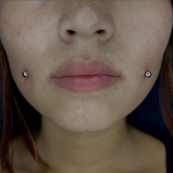 This may contain: a woman with piercings on her nose looking at the camera