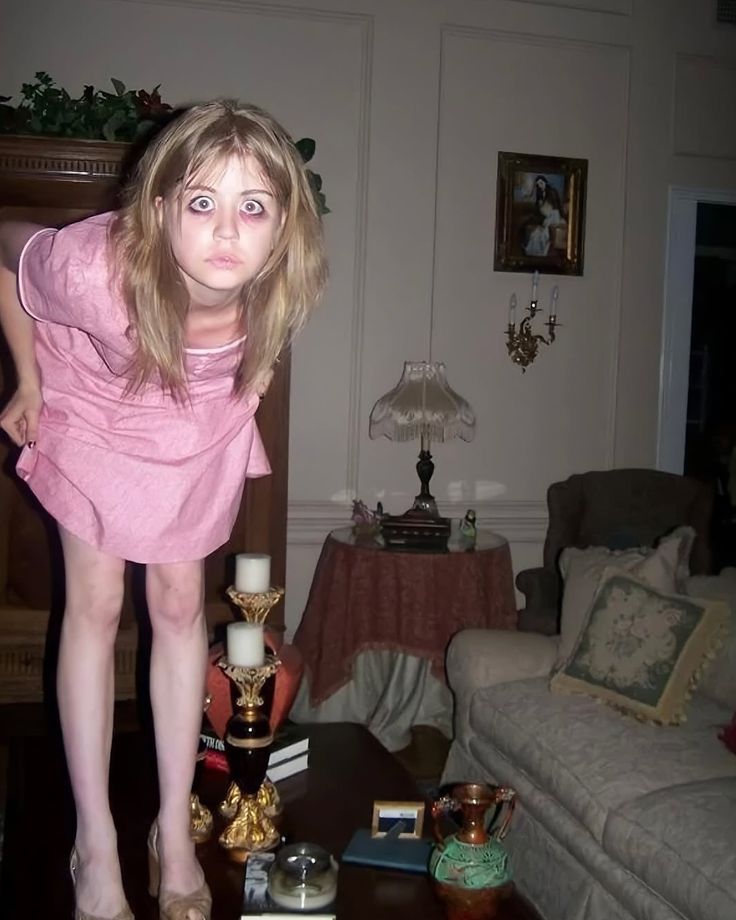 This may contain: a woman in pink dress standing on top of a coffee table next to a couch