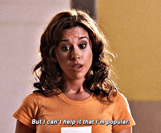 This may contain: a woman in an orange shirt with a surprised look on her face and the words, but i can't help that i'm popular