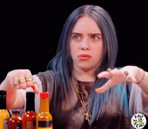 This may contain: a woman with blue hair sitting at a table in front of condiments and bottles
