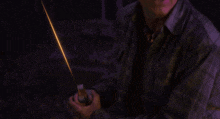 a young boy in a plaid shirt is holding a glowing object in his hand .