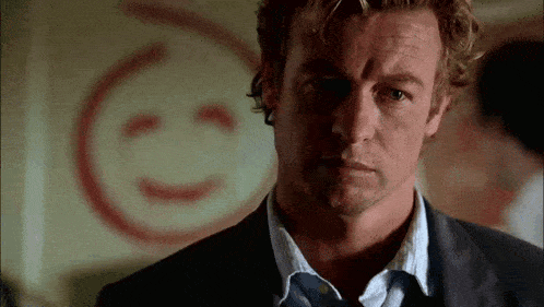 a man in a suit stands in front of a smiley face painted on the wall