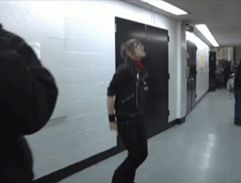 a man in a black jacket is jumping in a hallway next to a door